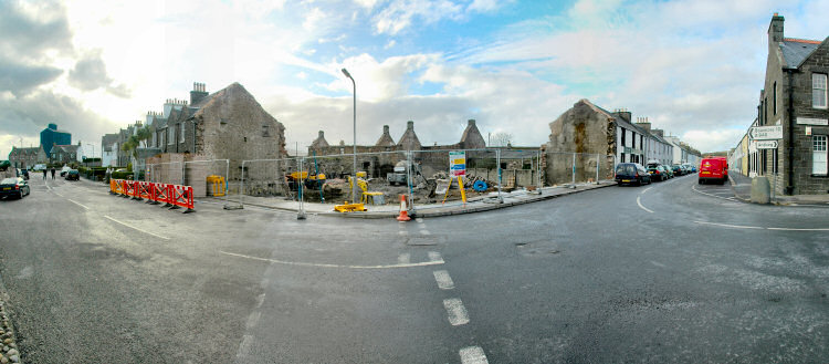 Panorama picture of a building site for a hotel, the foundations and some old outbuildings are visible