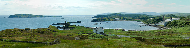 Picture of a panoramic view over a bay with the ruins of a castle and a whisky distillery (Lagavulin)