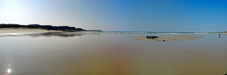 Picture of a panoramic view over a large beach with a shipwreck in the sand on a sunny day
