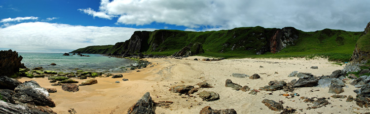 Picture of a panoramic view over a small beach in a cove with a waterfall